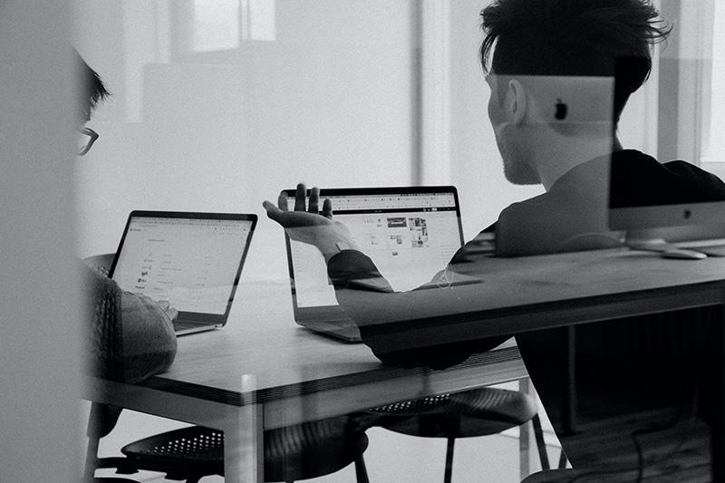 Two people in a consultation while staring at laptops.